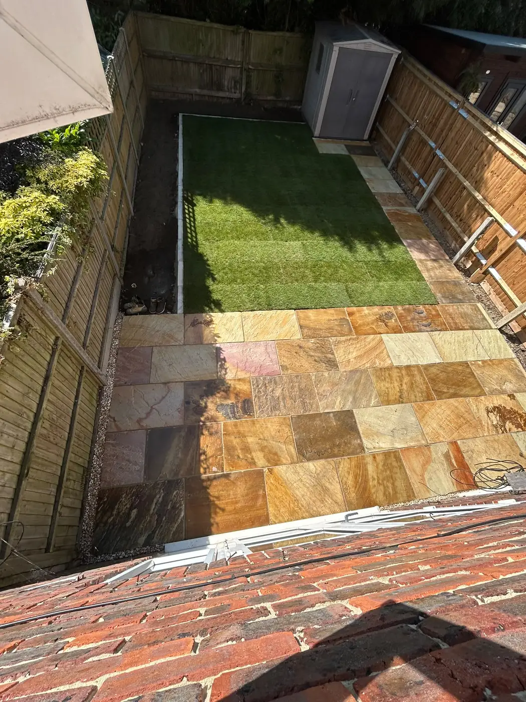 New lawn and Fossil Buff sandstone patio in the transformed garden