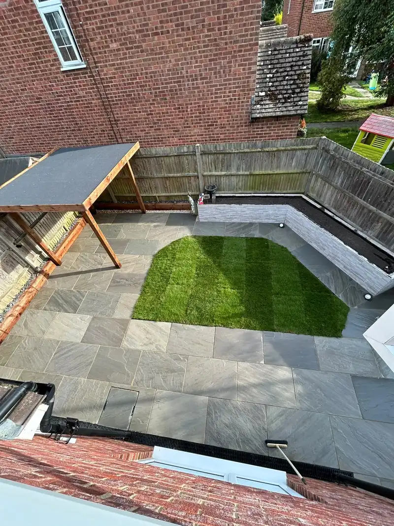 Grey sandstone patio, lawn and raised planter
