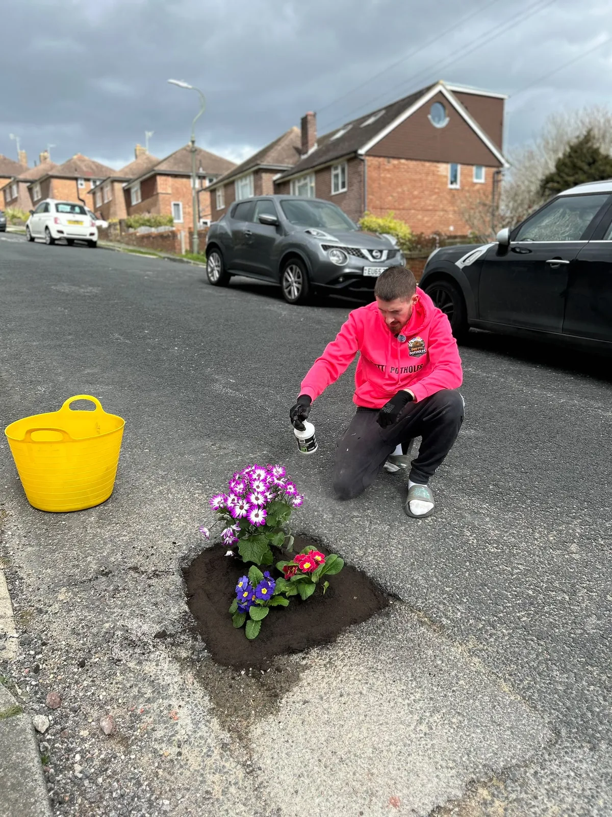 Harry Smith-Haggett planting flowers in a pothole during the Pretty Potholes campaign