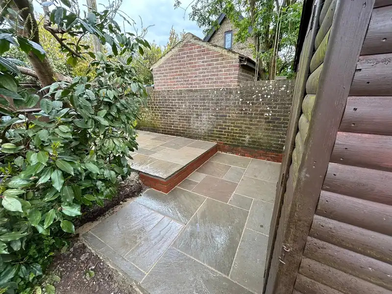 Sandstone paving meeting a raised brick garden step